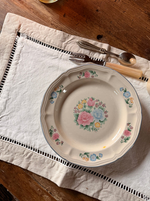 Set de table Albert 47 × 32 cm en linge ancien écru à bordure ajourée, présenté avec une assiette ancienne fleurie sur une table en bois – Maison Bellie.